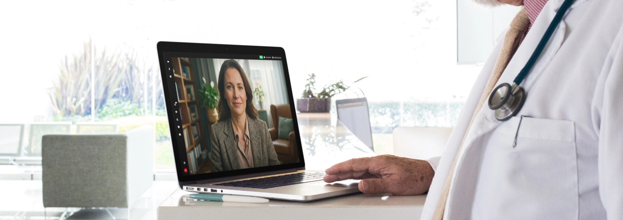 Ein Laptop steht auf einem Tisch. Der Bildschirm zeigt eine Frau mittleren Alters in ihrem Wohnzimmer. Vor dem Laptop steht ein männlicher Arzt mit Stethoskop, das ihm von der Schulter baumelt.